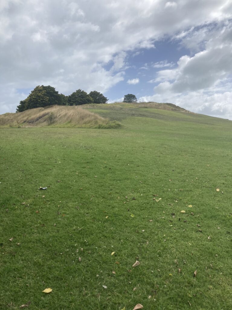 A photo from the bottom of Ohuiarangi, looking towards the summit. The clouds are grey.