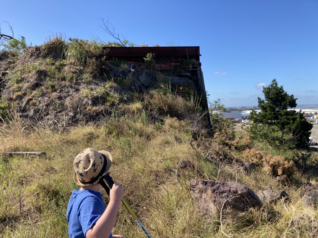 A rectangular concrete structure protruding from the side of the mountain. A small boy in a hat stands in the foreground.