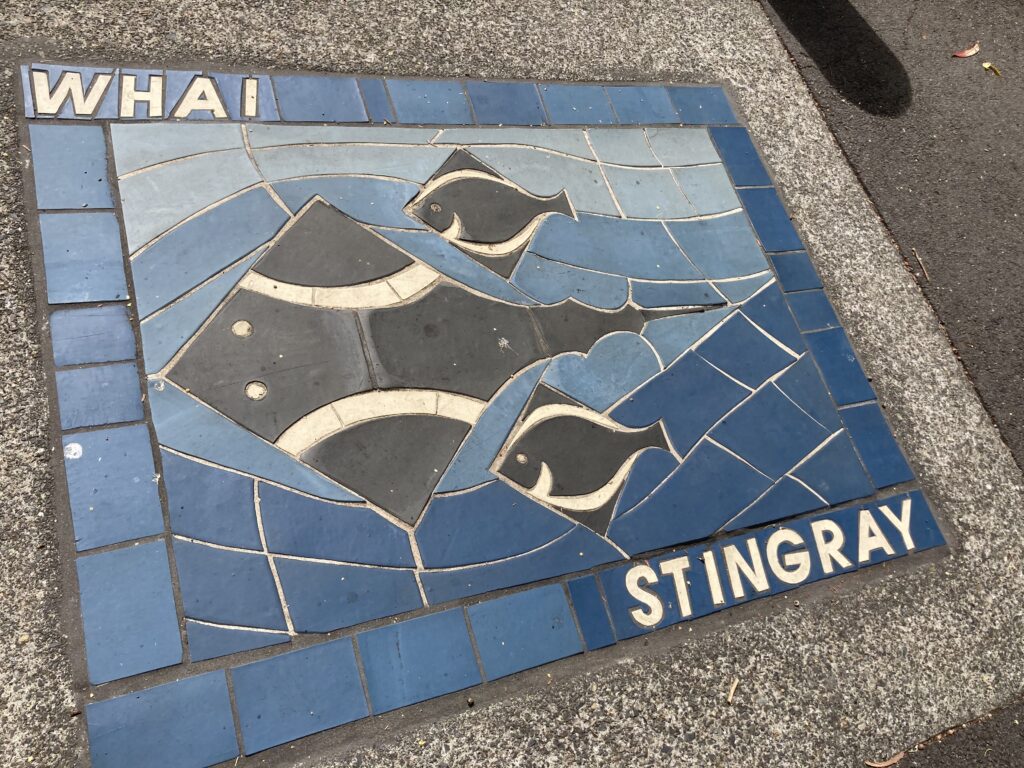 A large square mosaic set into the pavement. It is blue and shows three stringray. The word WHAI appears at the top, which is Maori for stingray.